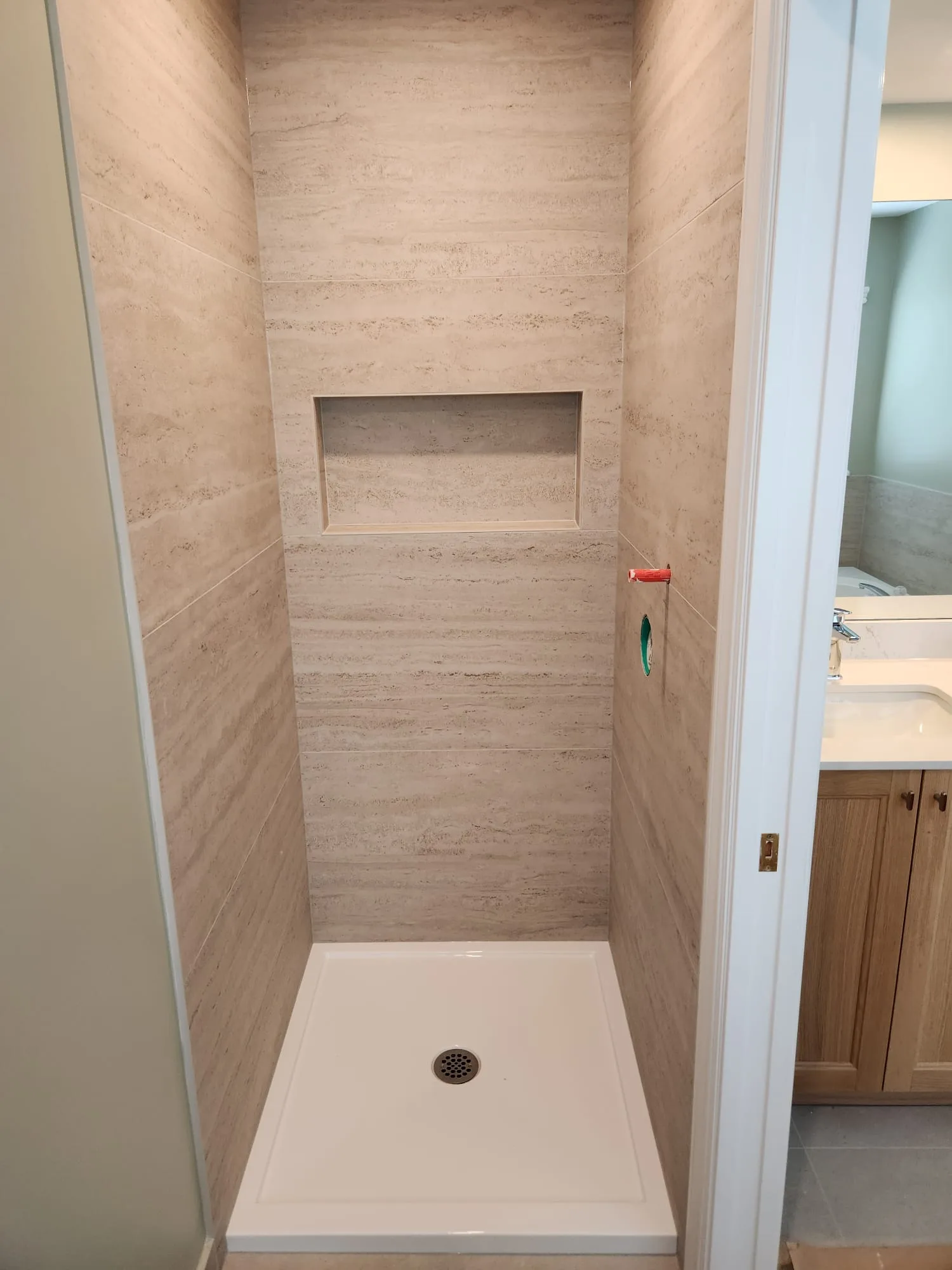 Before installation — travertine tile shower niche with shower pan, no glass enclosure