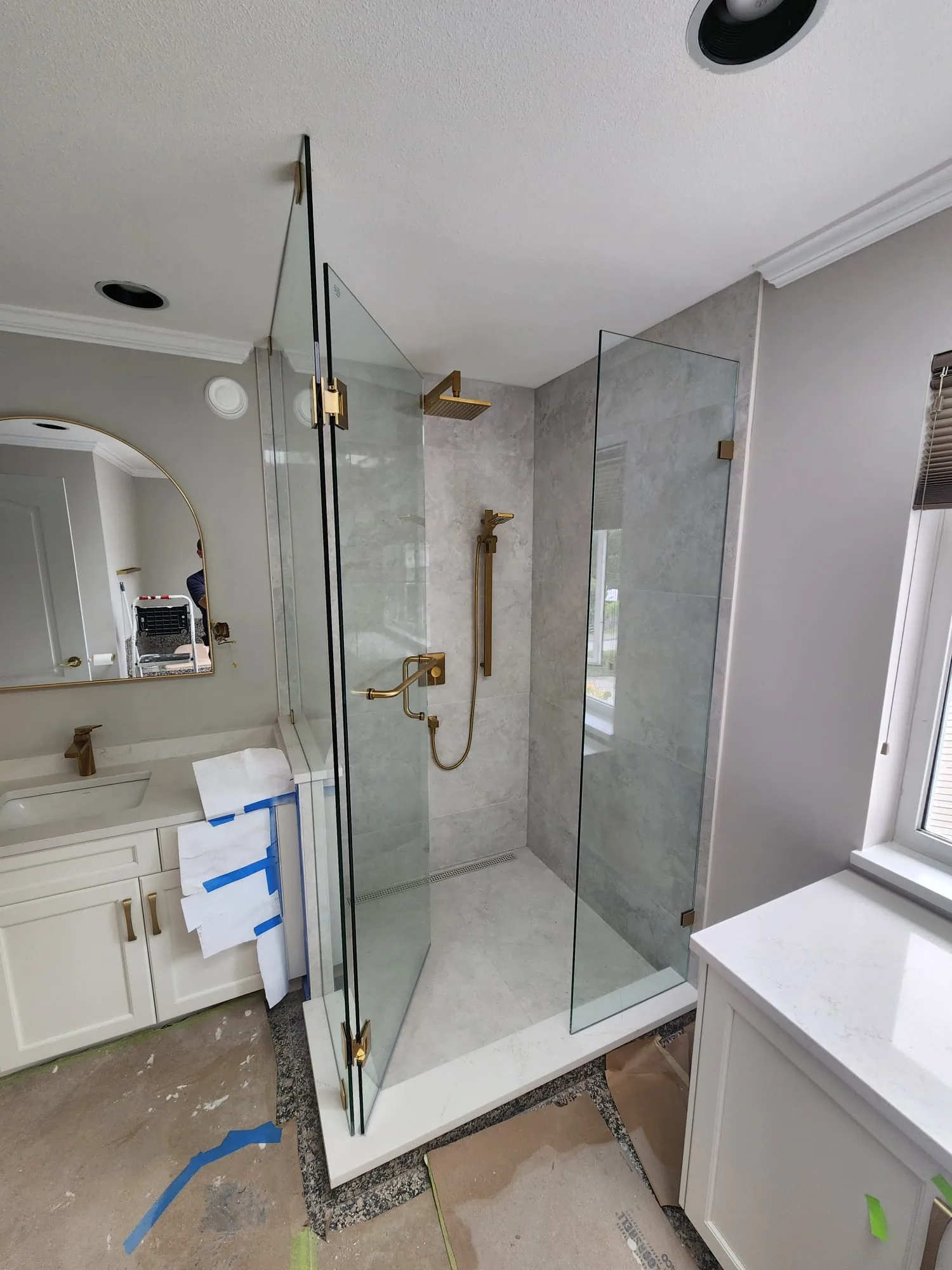 Side view of frameless shower enclosure with fixed panel and brushed gold hinges