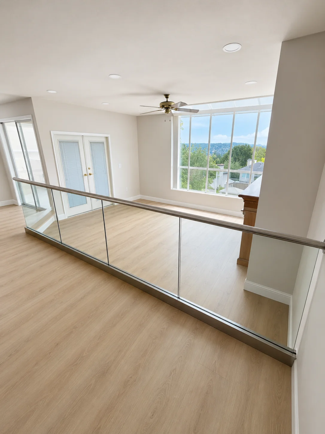 Full-length glass railing run with brushed stainless top cap rail — open second-floor hallway overlooking Port Moody