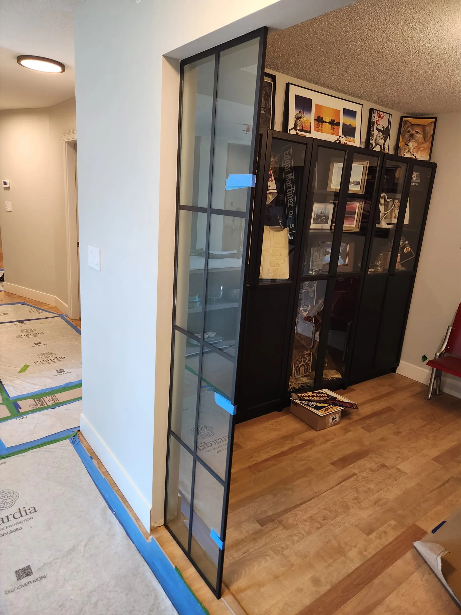 Installation from hallway side — black grid frame set in door opening, sports display cabinets and Edgar Martinez memorabilia visible beyond
