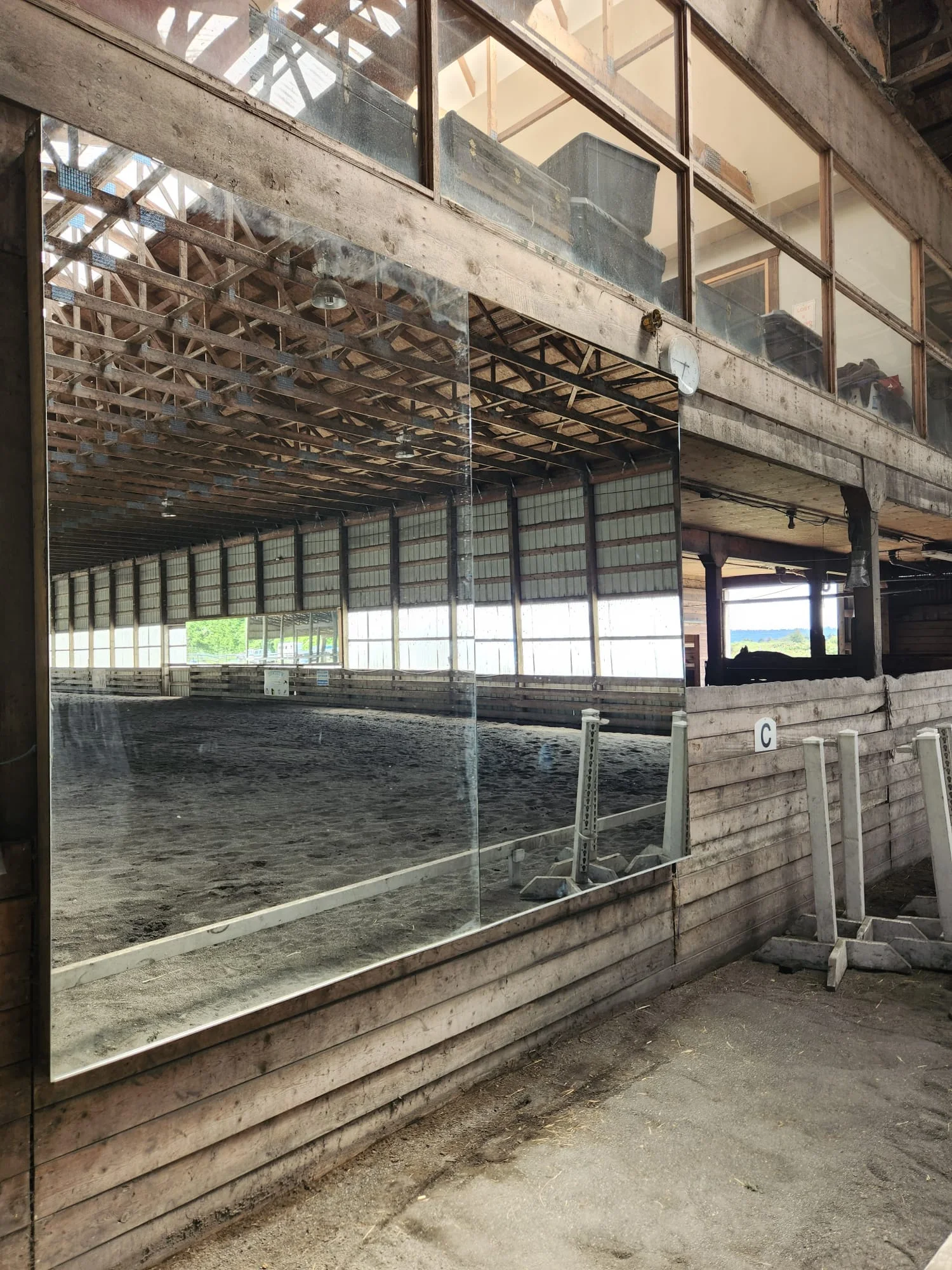 Straight-on view of completed arena mirror panels — J-channel base support, full arena reflected including dressage letter markers
