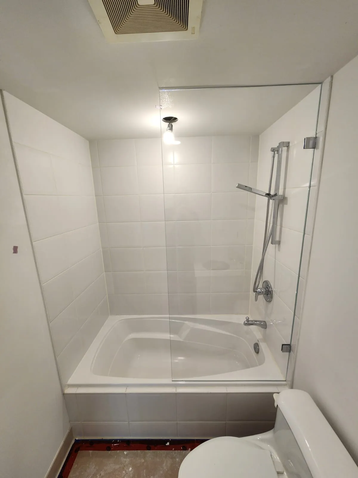 Completed low-iron glass tub panel installation, full-width view with chrome fixtures