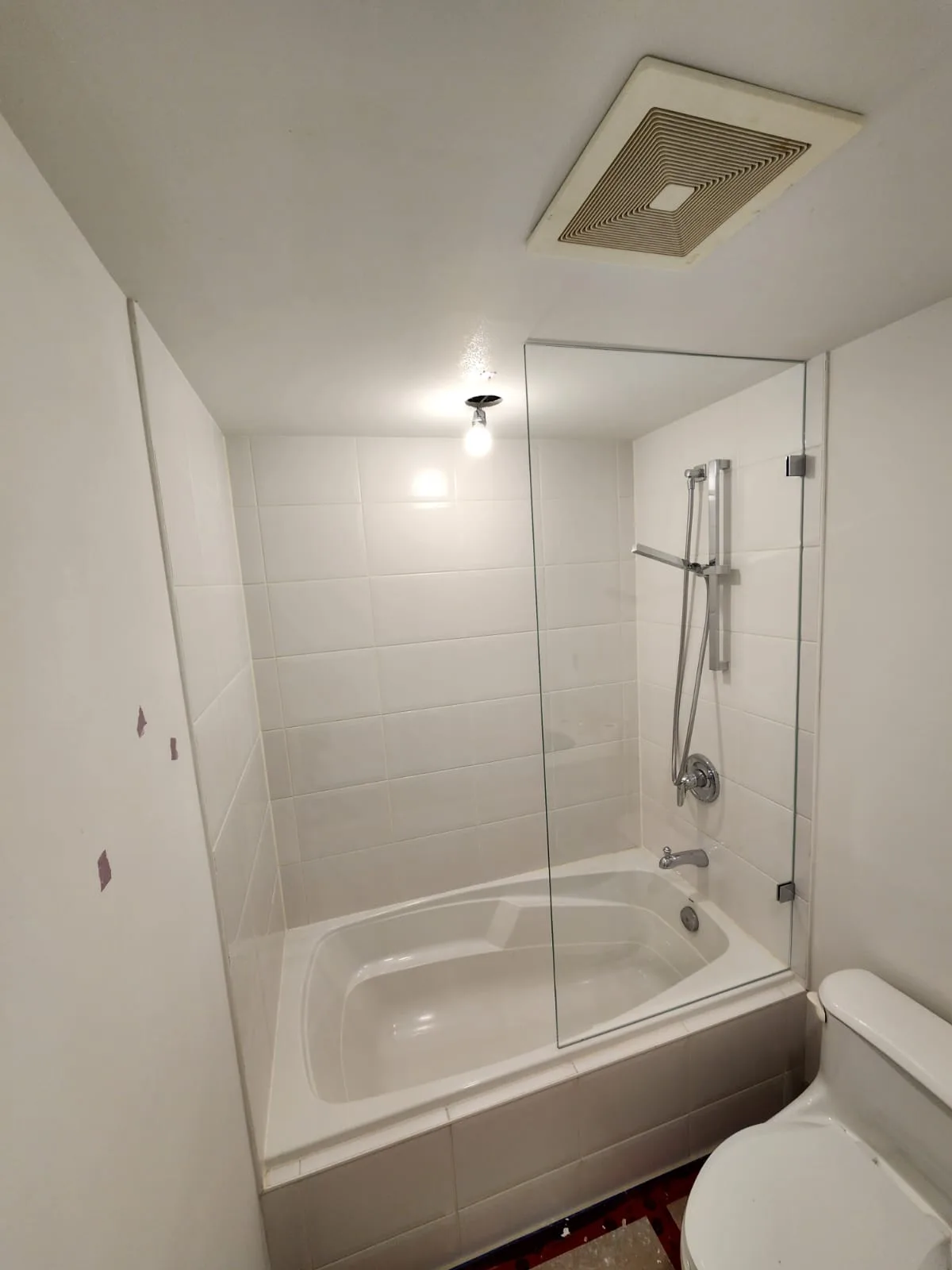 Low-iron glass tub panel — side angle showing panel height and polished chrome clamp hardware