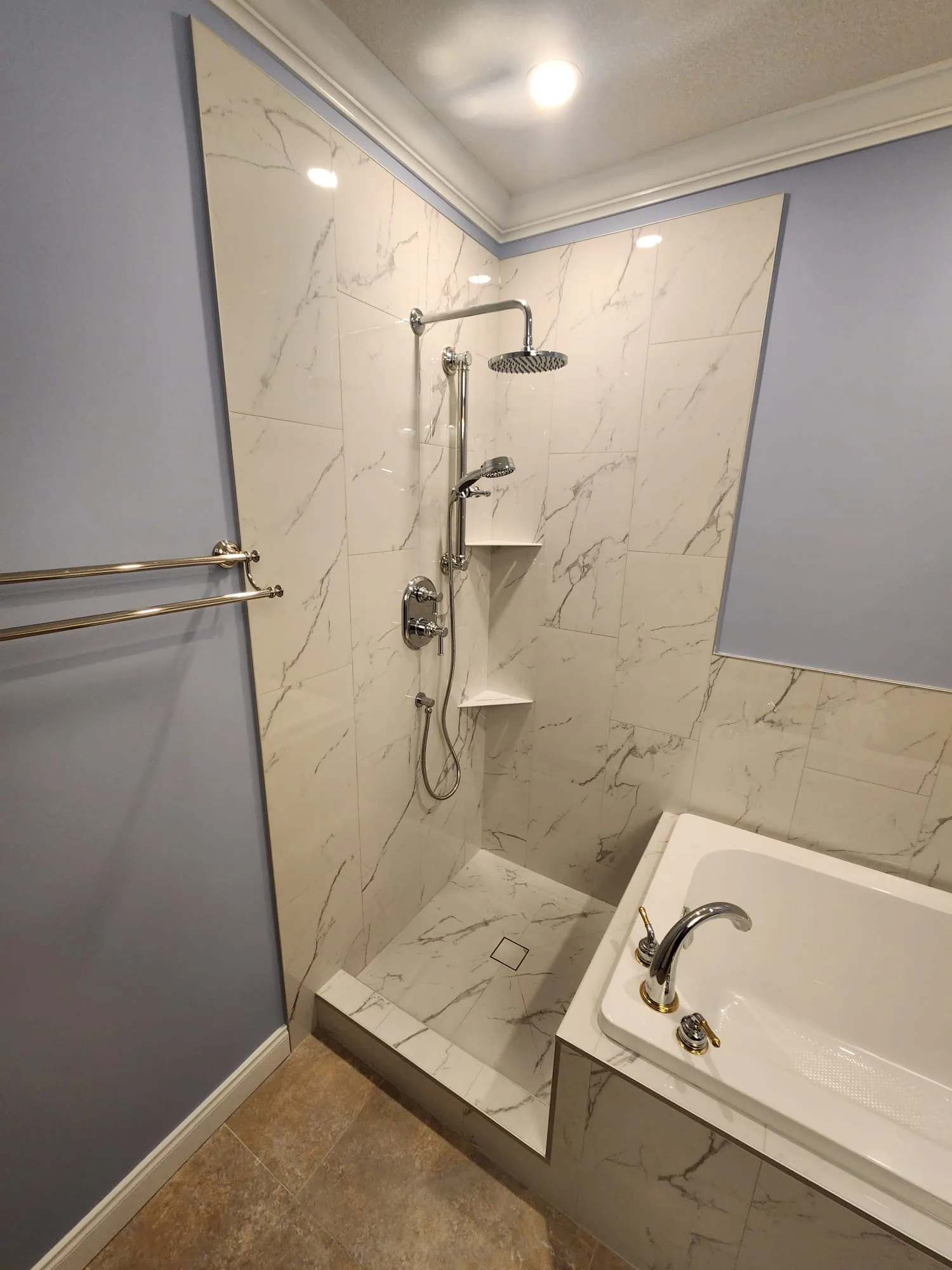 Before installation — full bathroom view showing Calacatta tile, soaker tub, and periwinkle walls